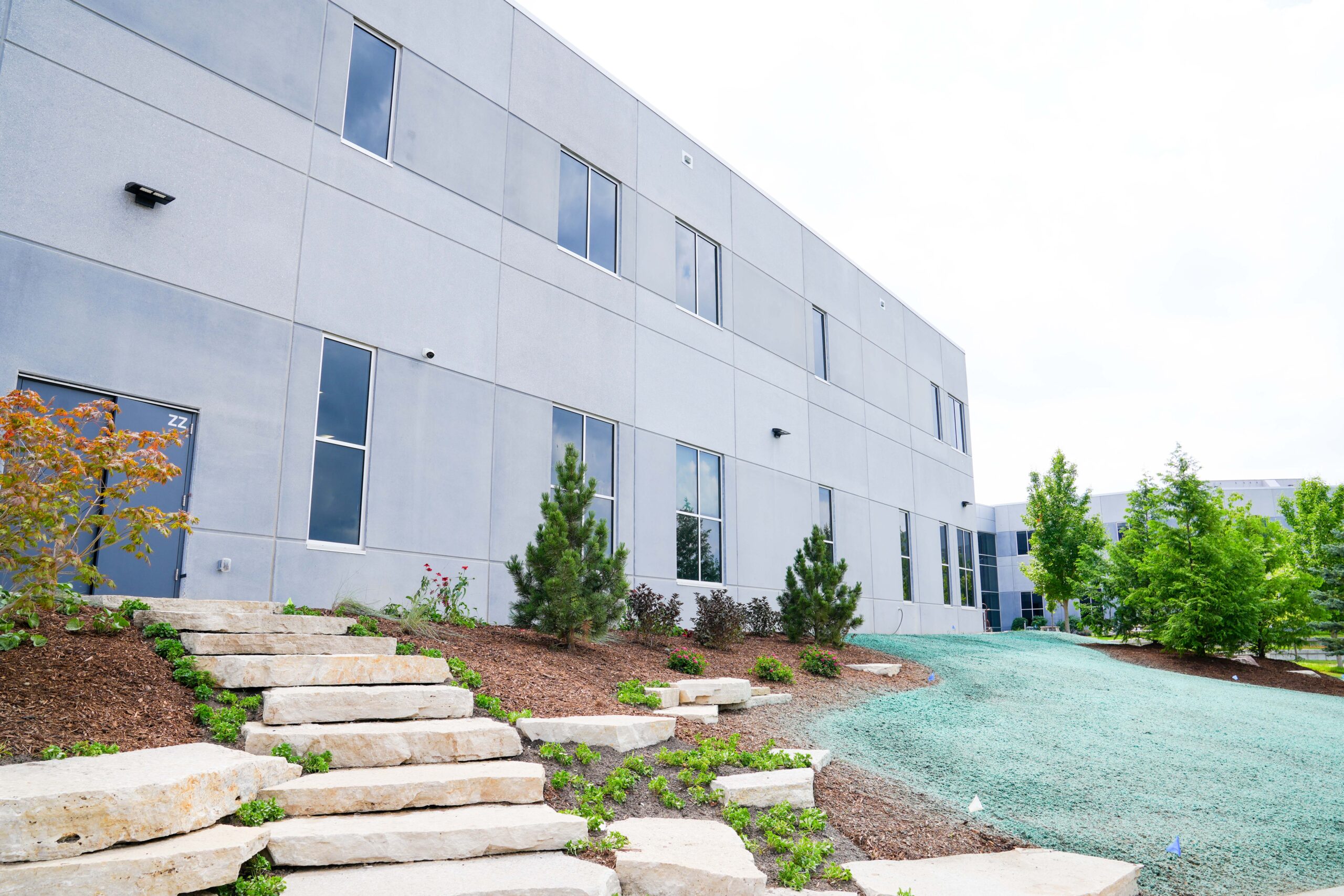 Exterior view of South Christian High School with landscaped stone steps, greenery, and Buist’s electrical contracting work integrated into the new facility.