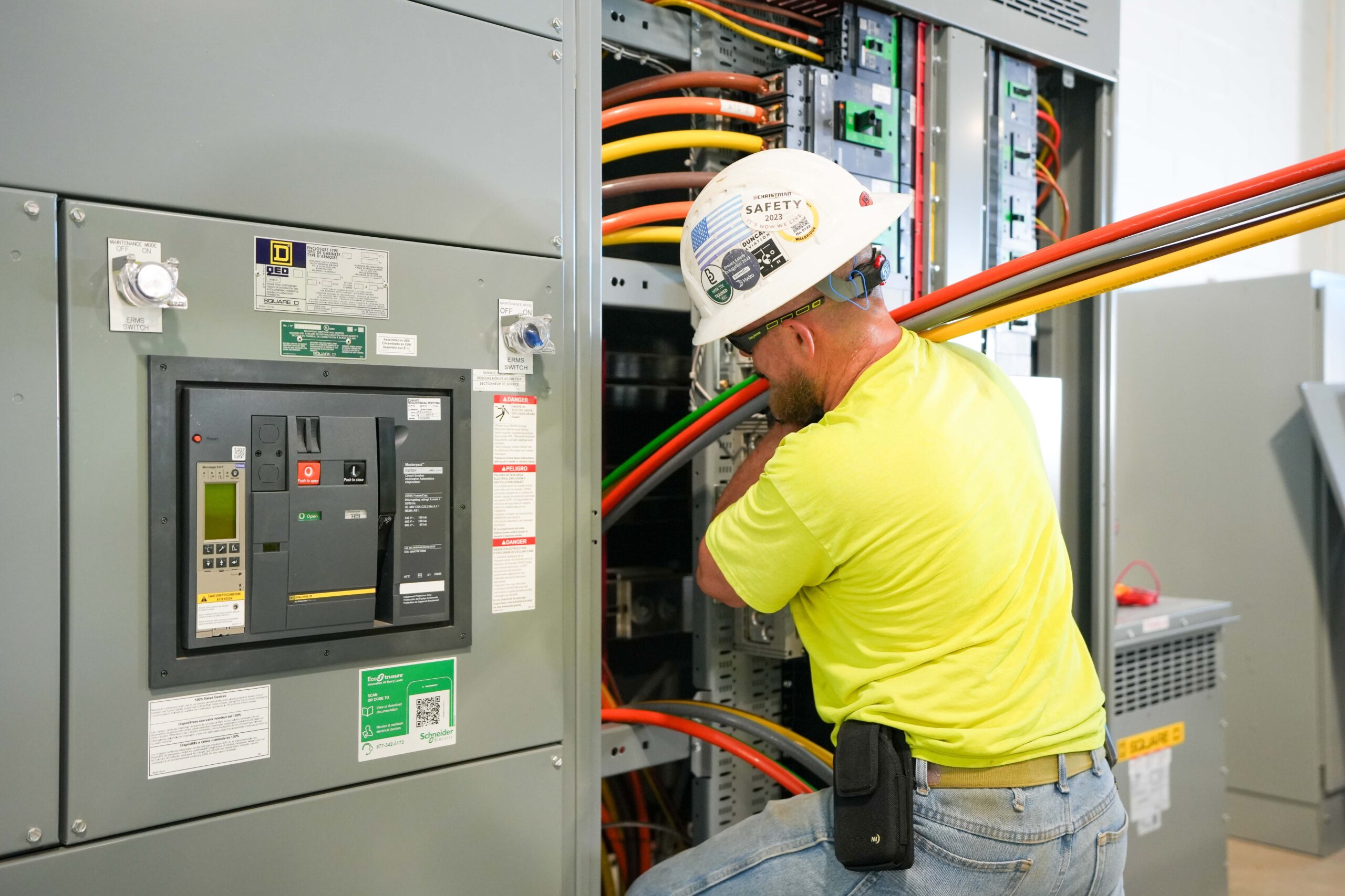 Buist electrician installing heavy electrical cables into switchgear system.