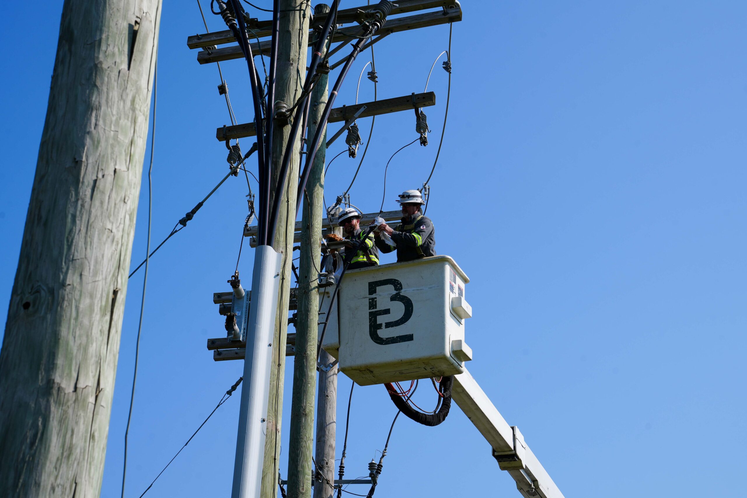 Buist Outdoor Utilities workers in a bucket truck repairing and maintaining overhead power lines.