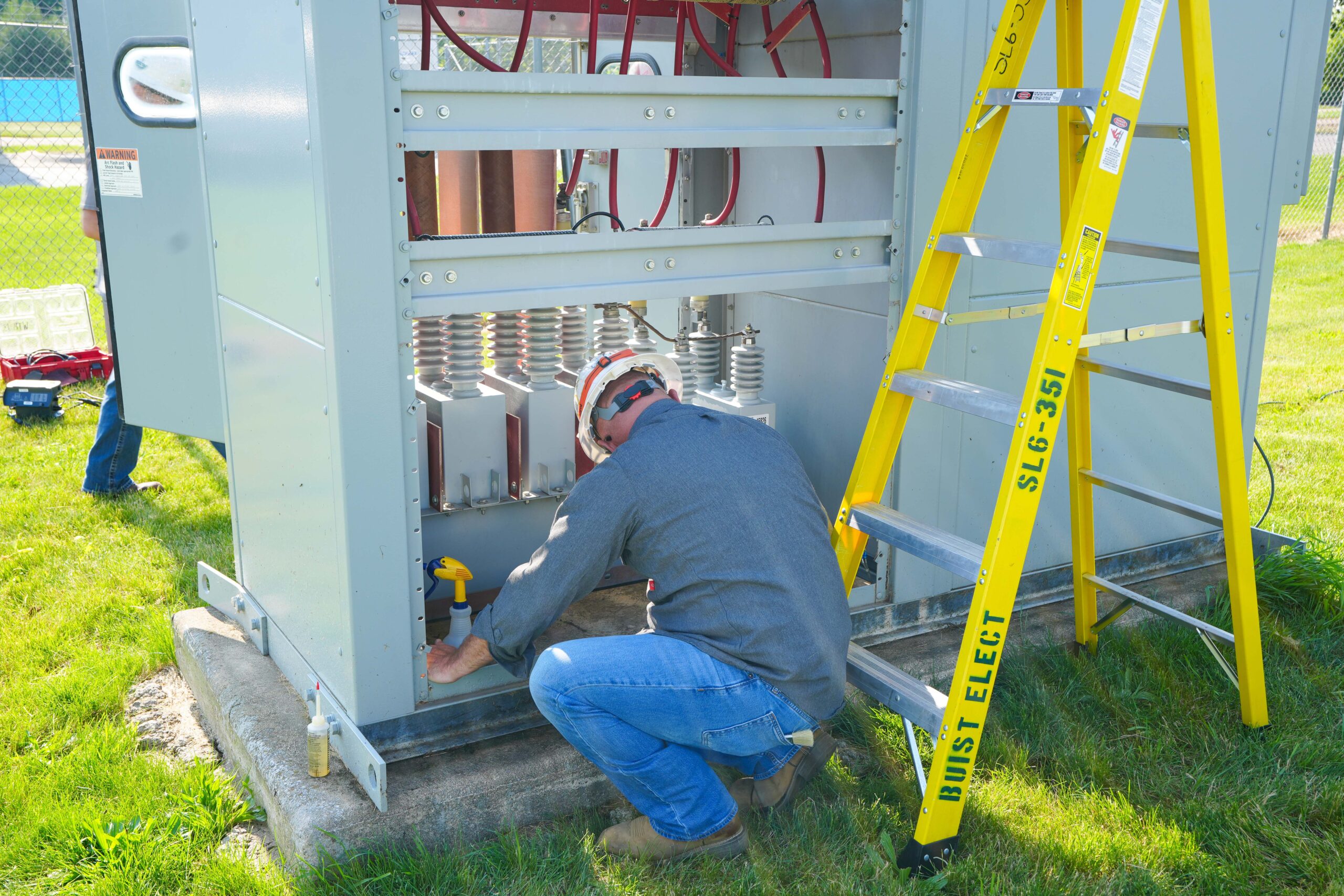 Buist technician conducting transformer field maintenance with tools and ladder.