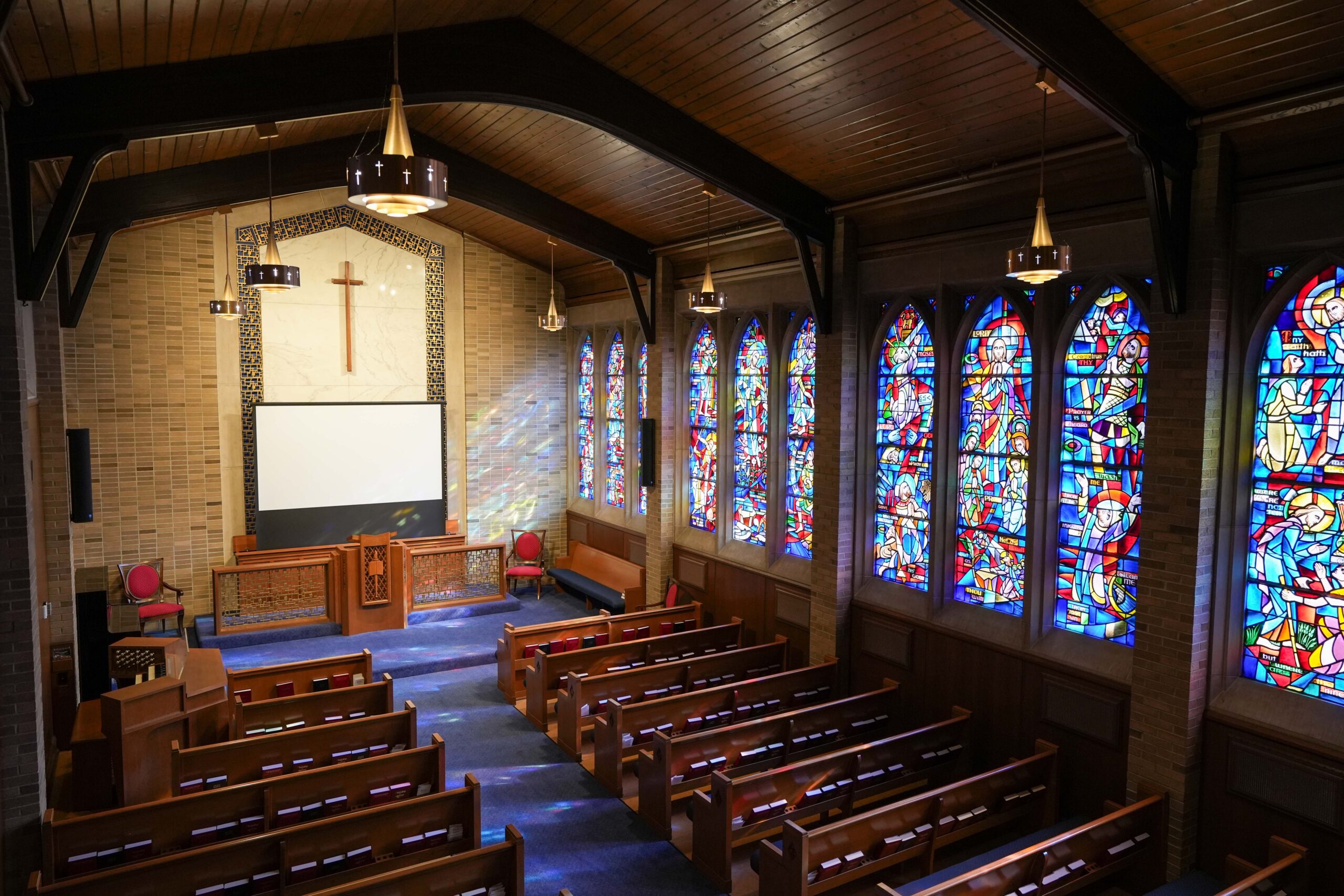 Chapel at LaGrave Avenue Christian Reformed Church in downtown Grand Rapids with stained-glass windows, pews, and updated lighting fixtures by Buist.