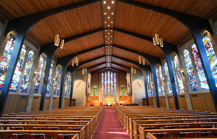 Sanctuary of LaGrave Avenue Christian Reformed Church in downtown Grand Rapids, MI, with colorful stained-glass windows and traditional wooden pews.