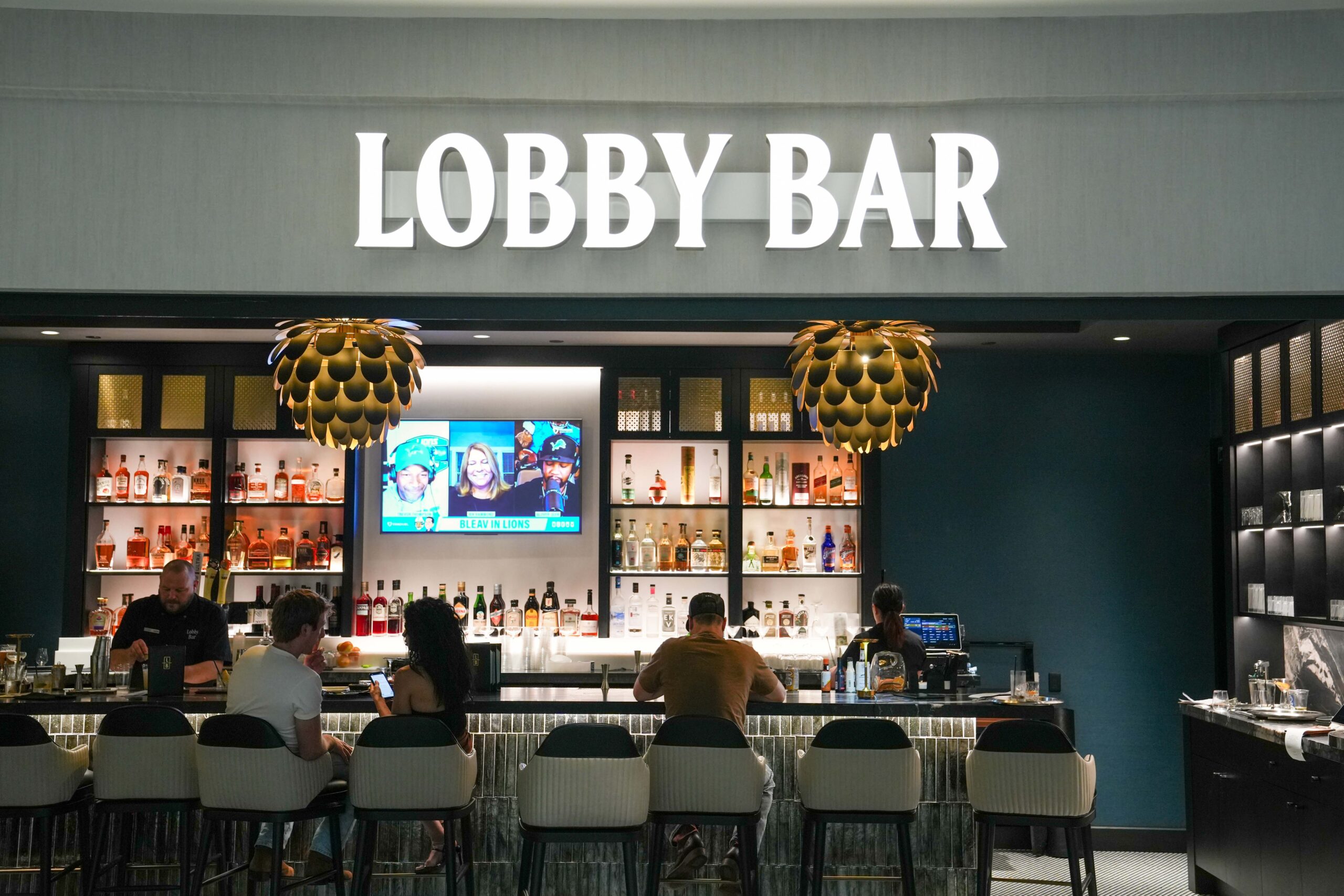 The Lobby Bar inside the Radisson Plaza Hotel featuring illuminated signage, modern lighting, and a fully stocked back bar.