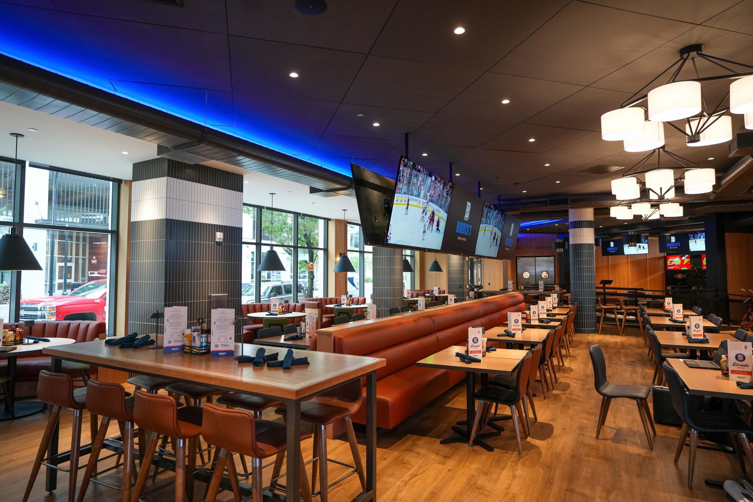Main dining area at Burdick’s Bar & Grill with booth seating, video walls, and accent lighting.