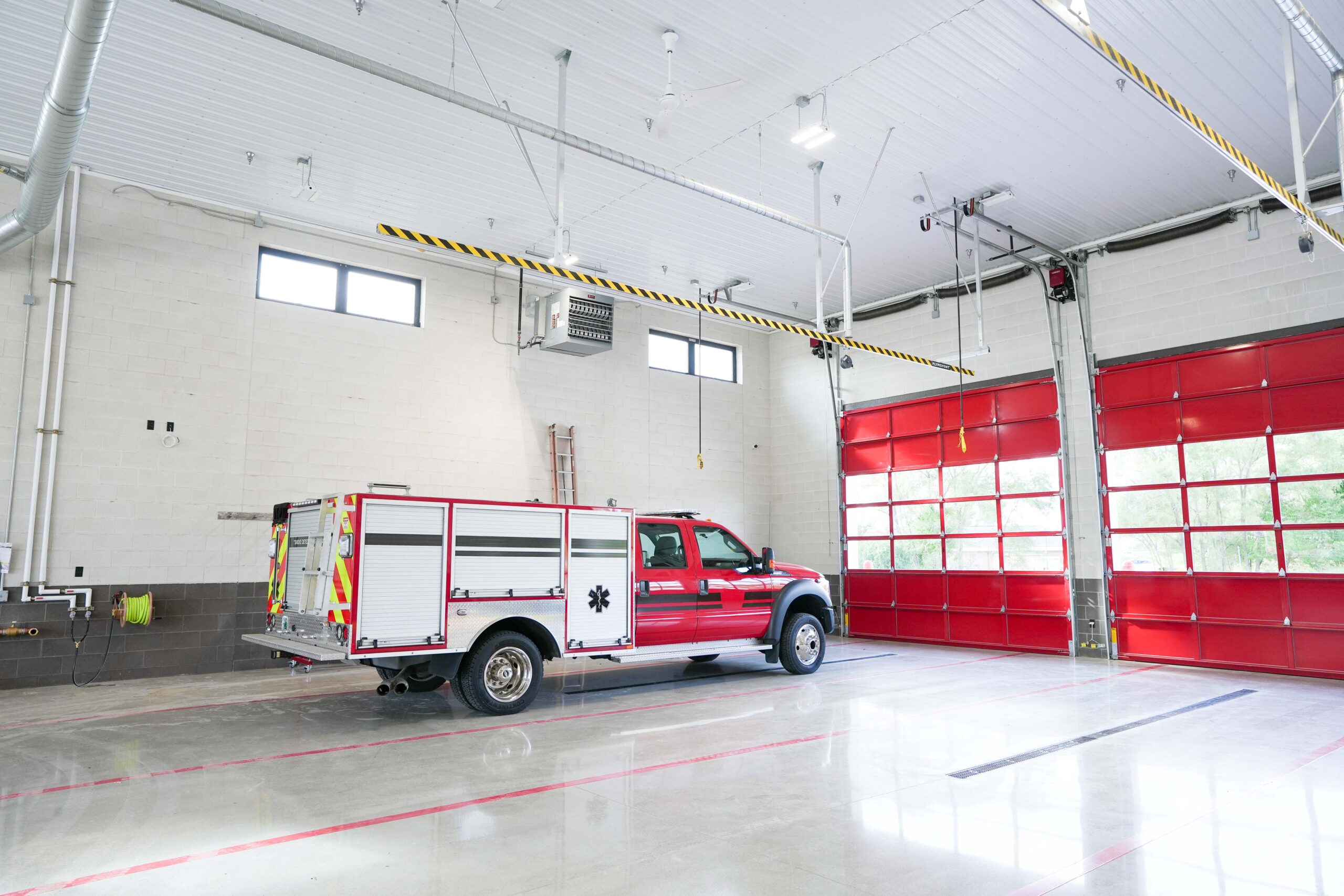 Interior view of Byron Township Fire Department’s apparatus bay featuring bright red doors and clean, functional work space.