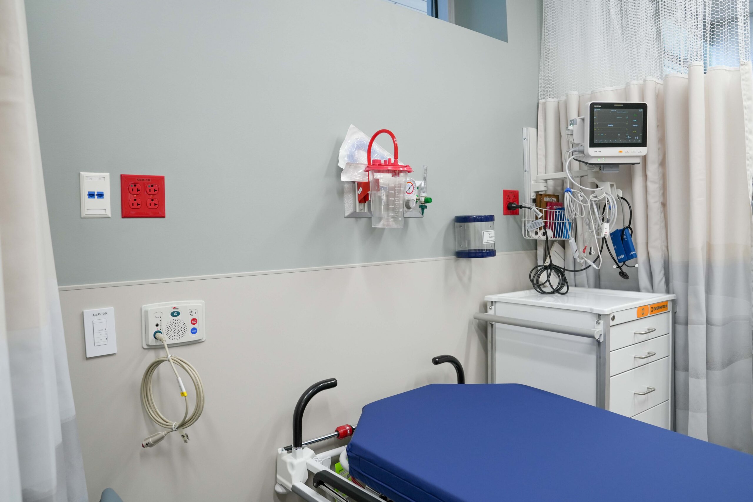 Close-up of patient room with medical equipment outlets monitors and electrical connections at Corewell Health Endoscopy Facility