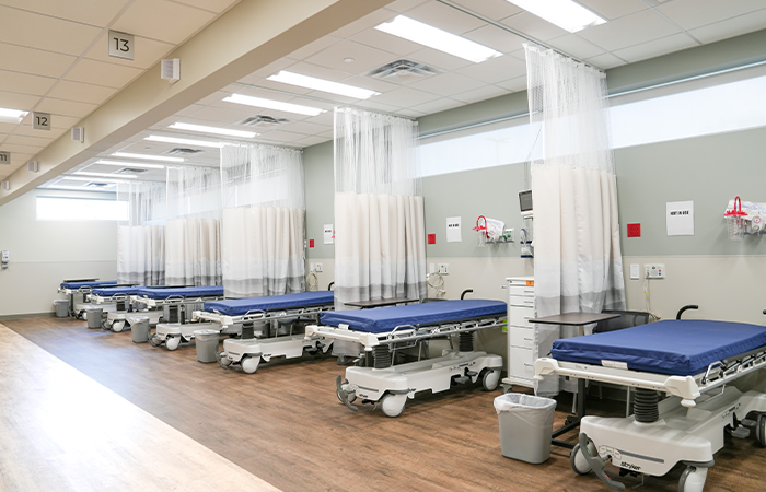 Interior recovery bay at Corewell Health Endoscopy Facility with hospital beds medical equipment and overhead lighting