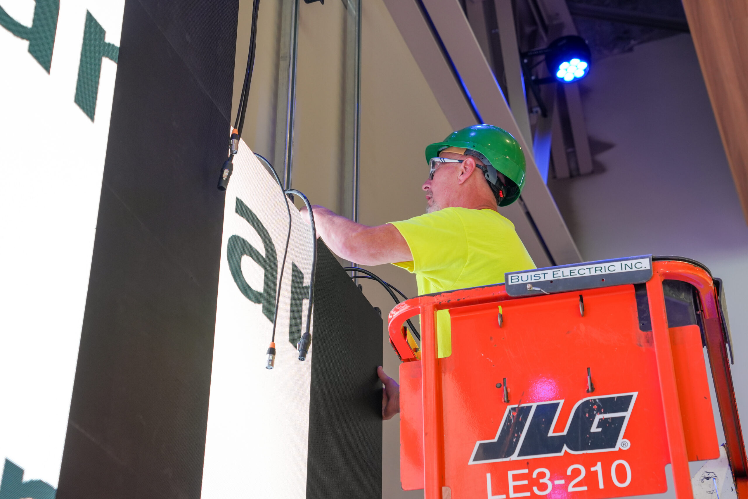 Buist electrician installing LED display panel using lift equipment for commercial audio visual installation