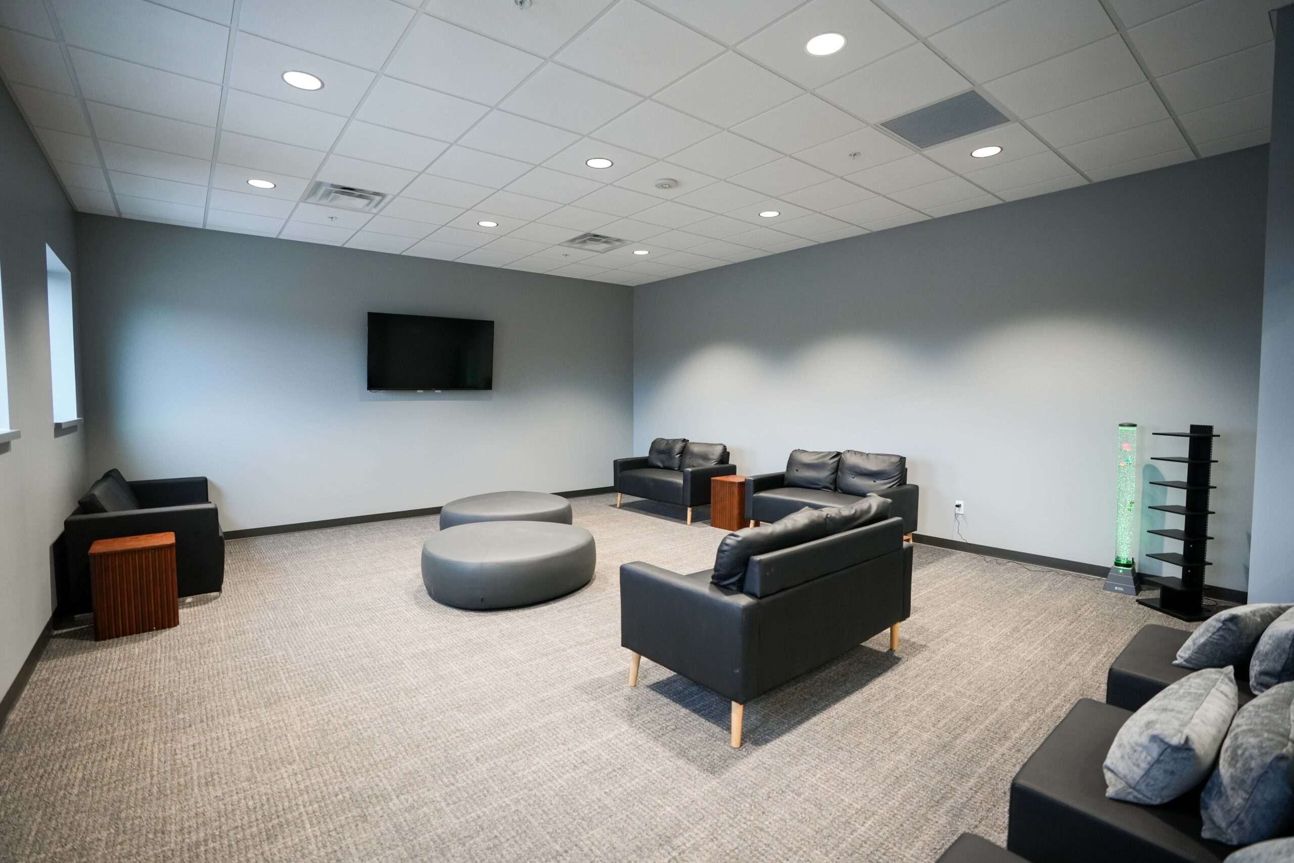 Lounge seating area with couches, tables, and wall-mounted display