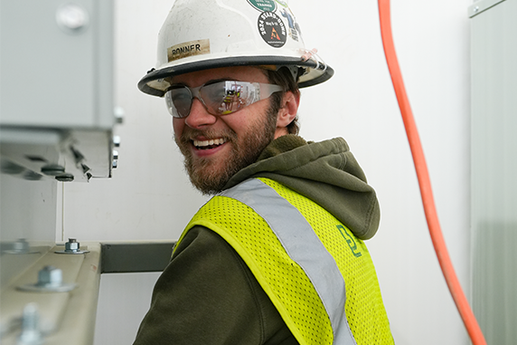 Buist electrical apprentice working on commercial electrical equipment while wearing safety gear in West Michigan.