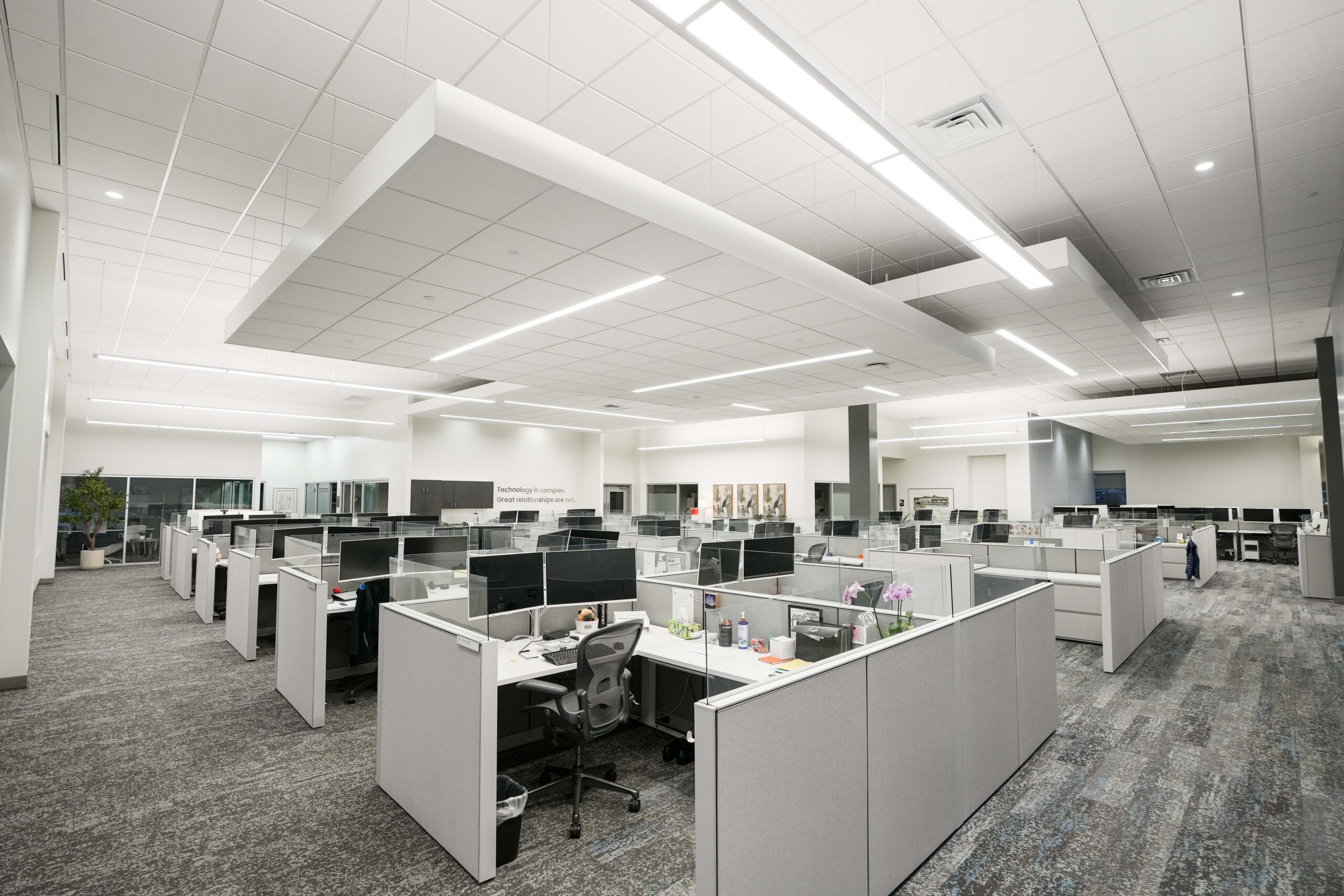 Large open office workspace with cubicles, suspended architectural lighting, and modern commercial interiors.