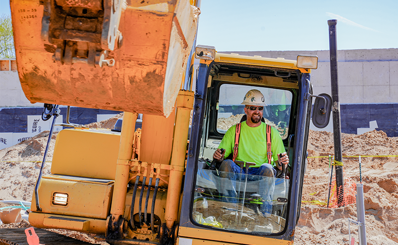Buist Outdoor Utilities team member operating an excavator on a commercial construction site in West Michigan.