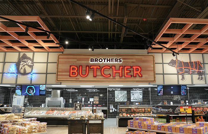 Retail butcher department featuring custom illuminated signage and decorative lighting by Buist.