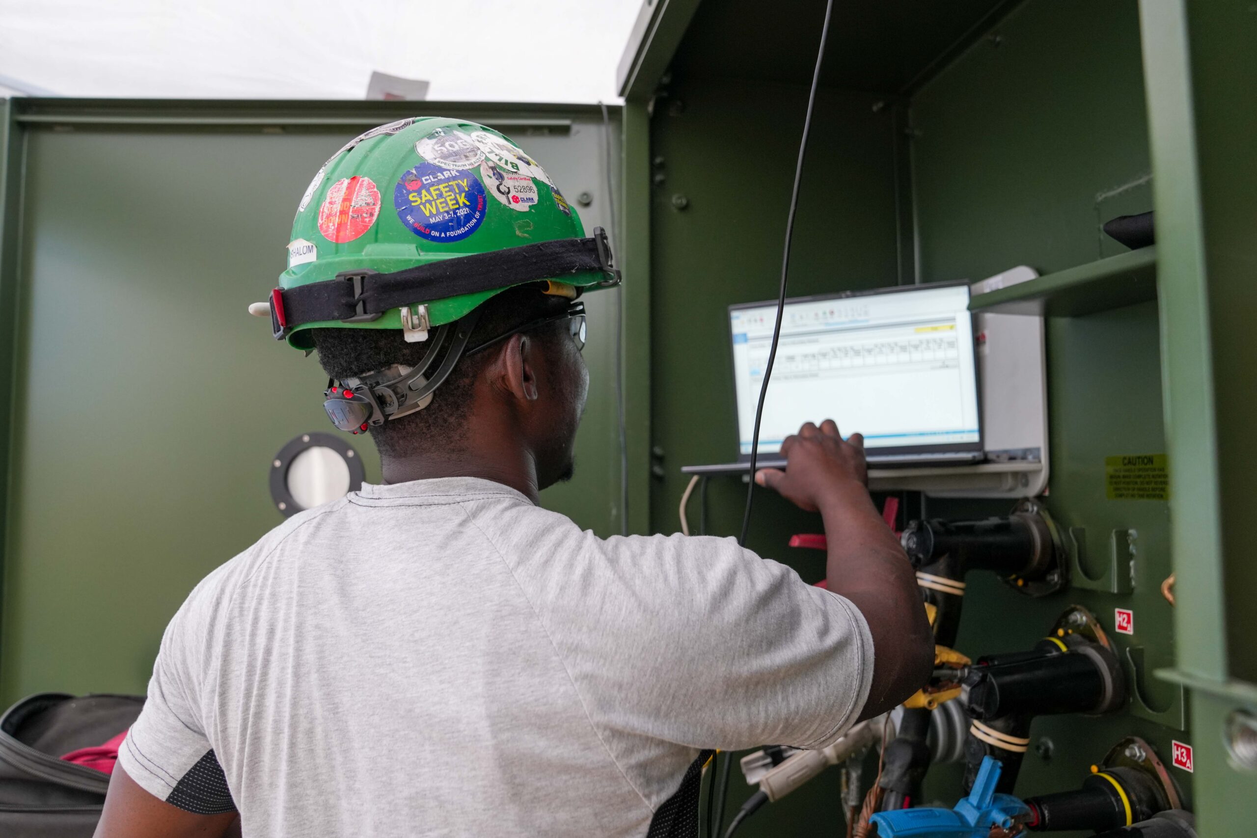 Buist technician reviewing electrical testing data on a laptop while connected to medium-voltage equipment.