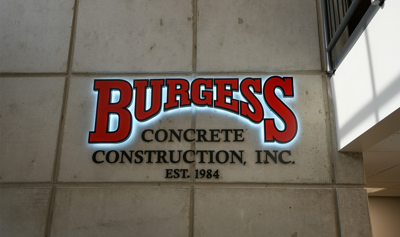 Illuminated Burgess Concrete Construction wall sign inside the renovated office facility in Moline, Michigan.