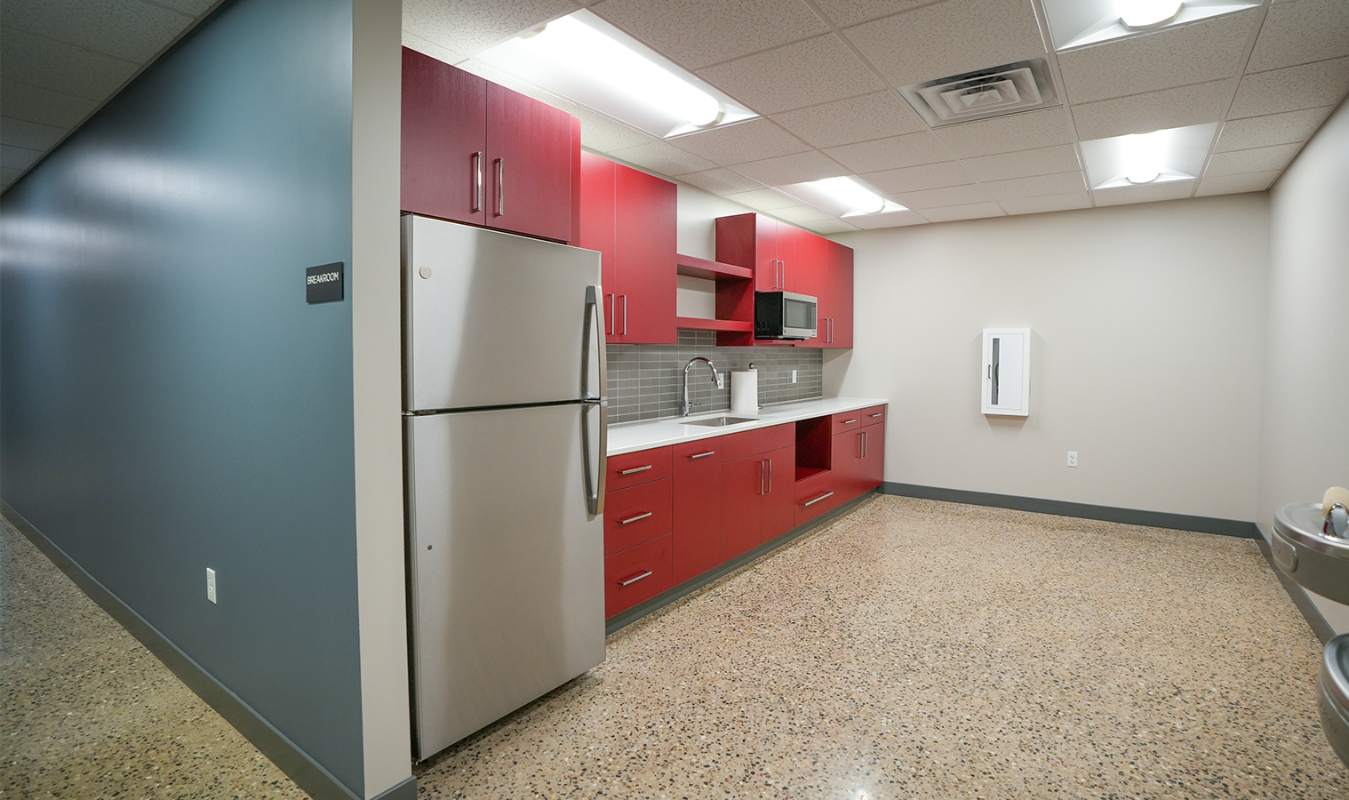 Employee breakroom with red cabinetry, LED lighting, and modern finishes inside Burgess Concrete Construction's office.