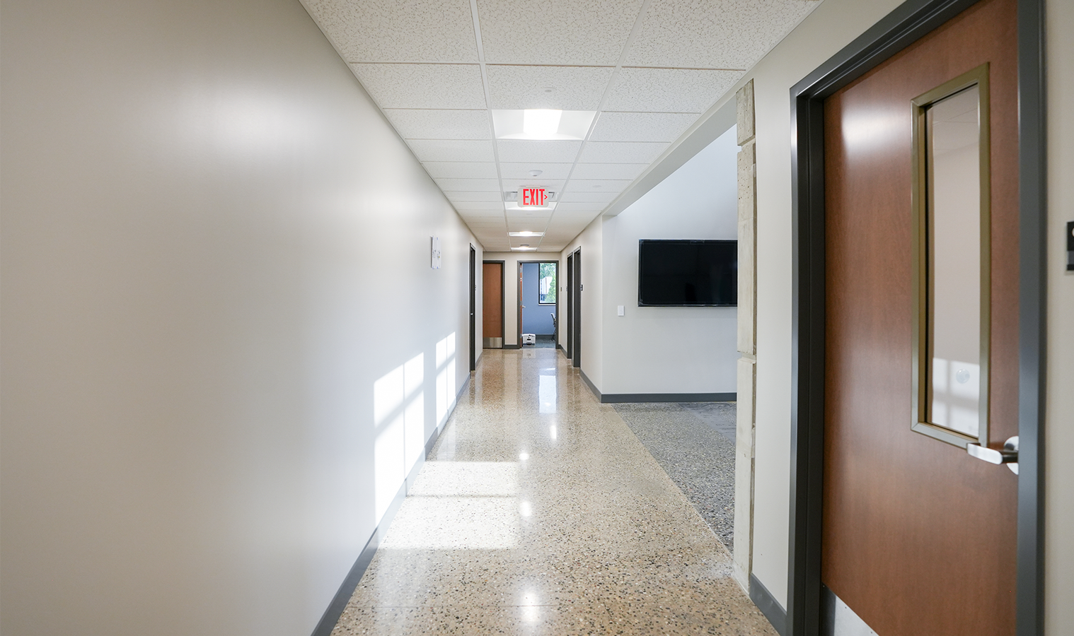 Interior hallway with modern lighting, polished concrete floors, and office entrances at Burgess Concrete Construction.