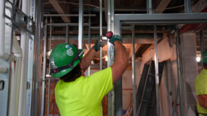 Buist electrician installing electrical components in metal wall framing at Alpha Grand Rapids.