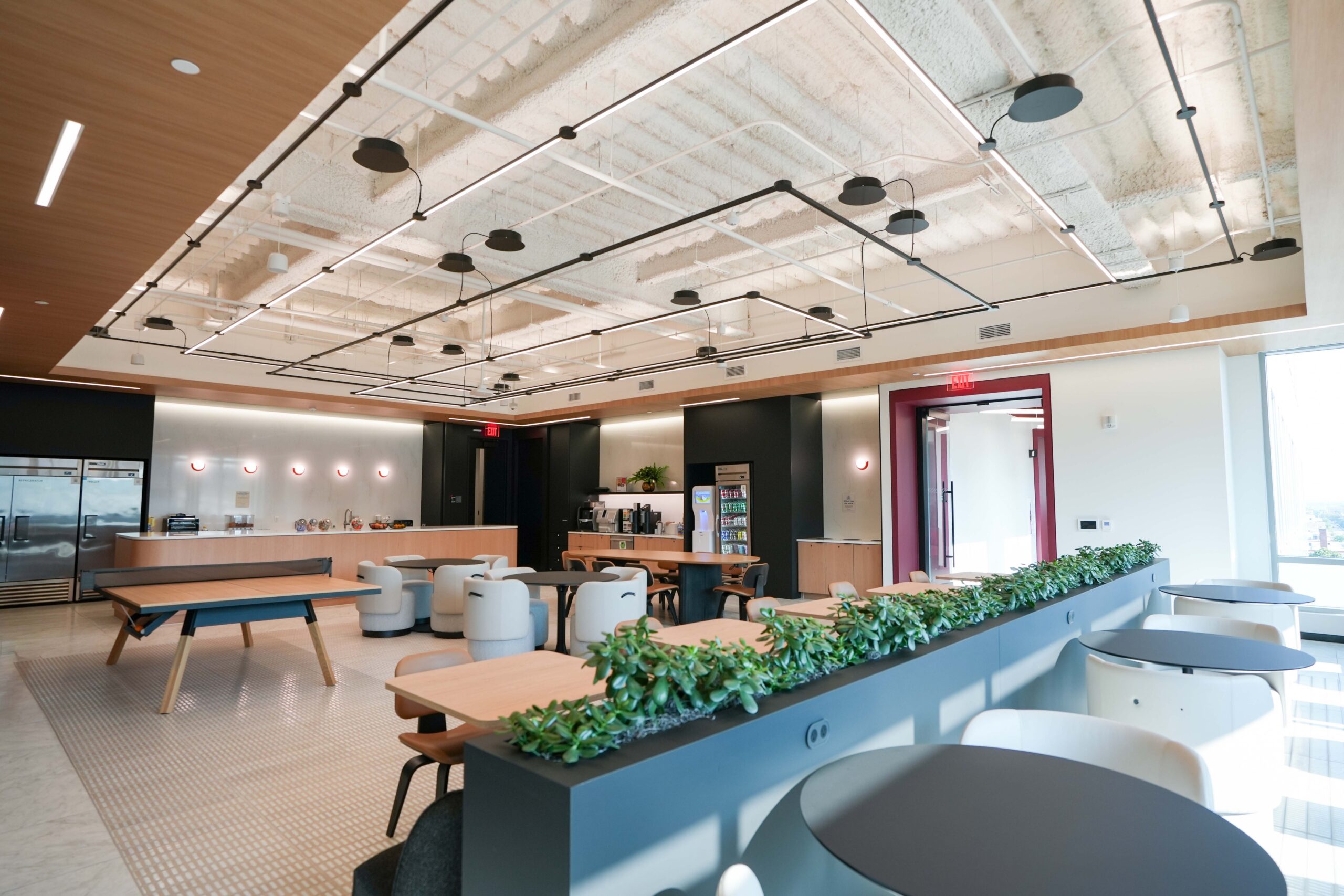 BDO office breakroom with suspended linear lighting, open ceilings, and collaborative seating.