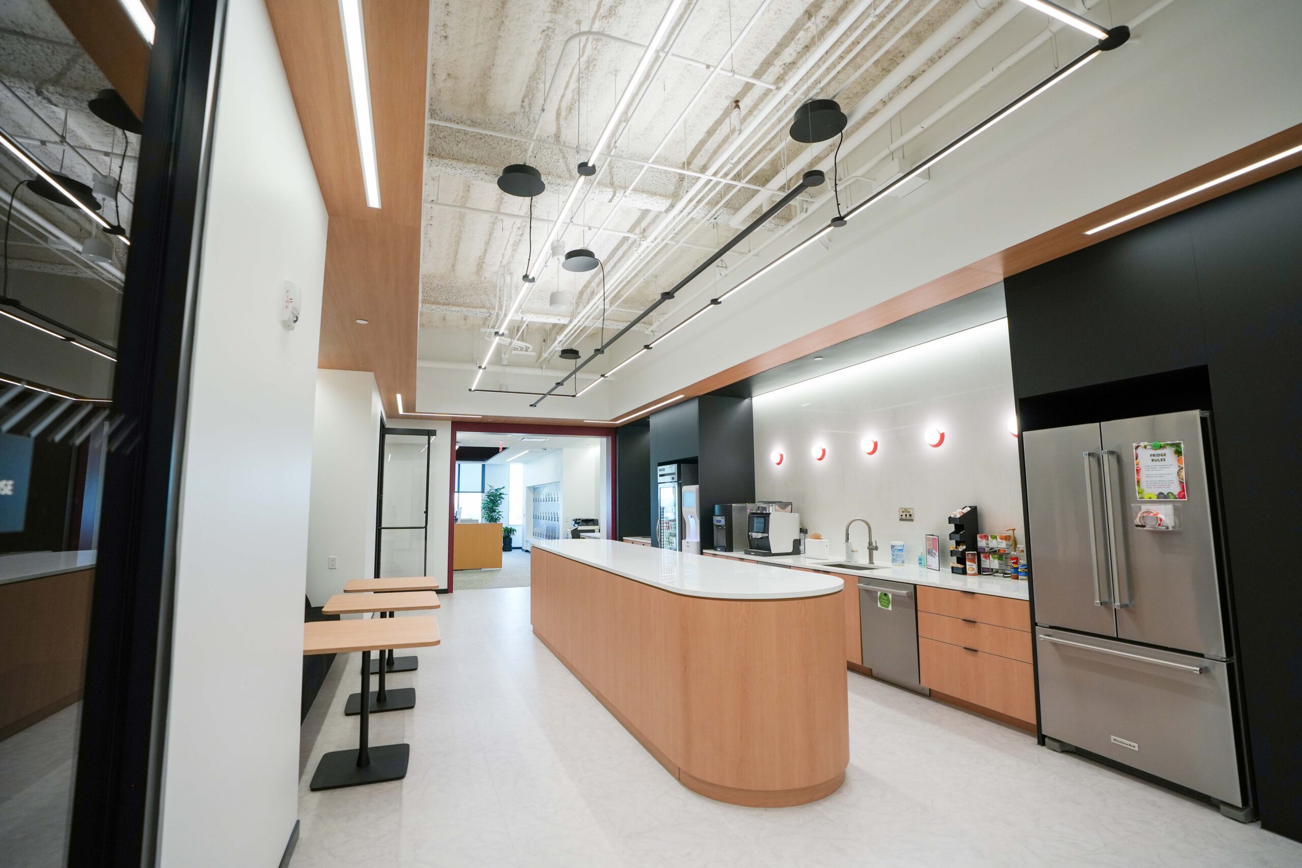 BDO office kitchen featuring linear lighting, exposed ceilings, and wood cabinetry.